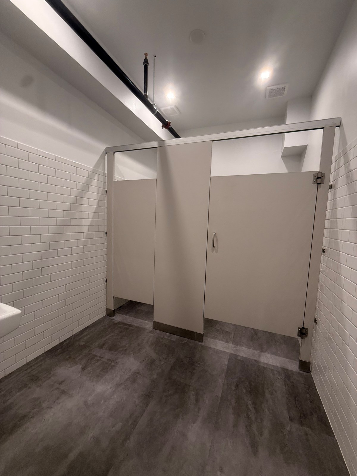 School restroom with large white wall tile and gray floor